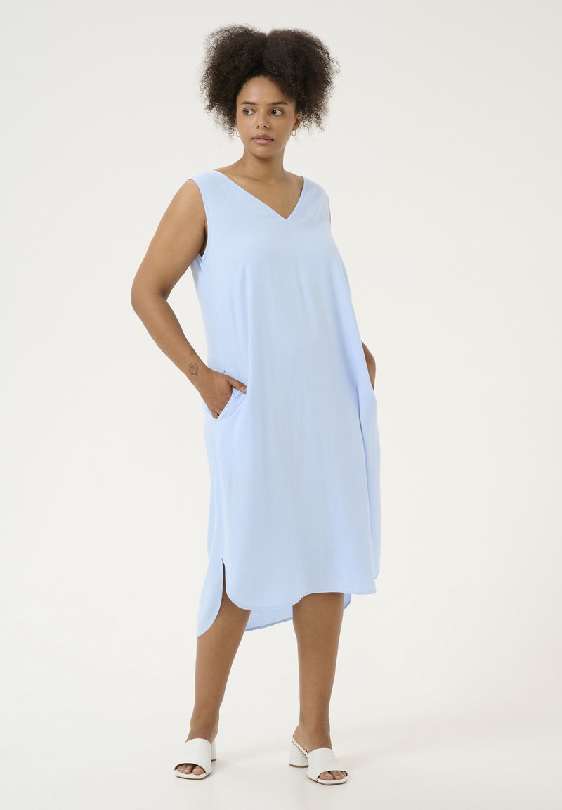 Helles blaues, ärmelloses Kleid mit V-Ausschnitt, seitlichen Taschen und asymmetrischem Saum. Glattes Gewebe mit lockerer Passform und dezentem Glanz.