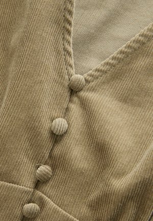 Tissu en velours côtelé beige présentant un décolleté en V et des boutons ronds texturés le long de l'avant, avec une subtile texture de côtes verticales.