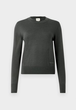 Pull en maille gris foncé avec un col rond et des manches longues. Présente un ourlet côtelé et une discrète marque en bas à gauche.