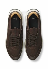 Braune Netzsneaker mit Gummisohlen, runden Zehen, Schnürverschluss und minimalistischem Design. Markierung auf der Innensohle sichtbar.