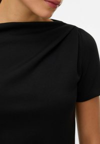 Črn kratki rokav s okroglim izrezom, ki ima gladko tkanino in subtilen drapiran detajl na rami.