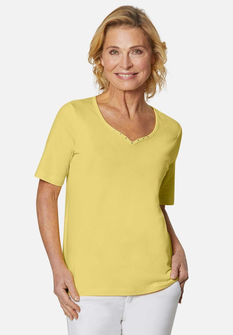 Geel T-shirt met korte mouwen en een V-halslijn, versierd met studs. Gemaakt van zachte stof, met een comfortabele pasvorm en een effen kleurdesign.