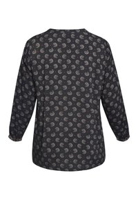 Langærmet bluse i mørkt stof med et gentaget swirly- og prikmønster i beige og rød. Løs pasform med elastiske manchetter.