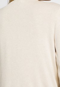 Beige Strickpullover mit weicher Textur, schlichtem Design und Rundhalsausschnitt, von hinten ohne Verzierungen betrachtet.
