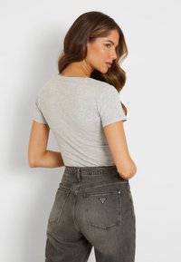 Gray short-sleeve t-shirt with a round neckline, paired with high-waisted dark gray jeans featuring a triangular logo on the back pocket.