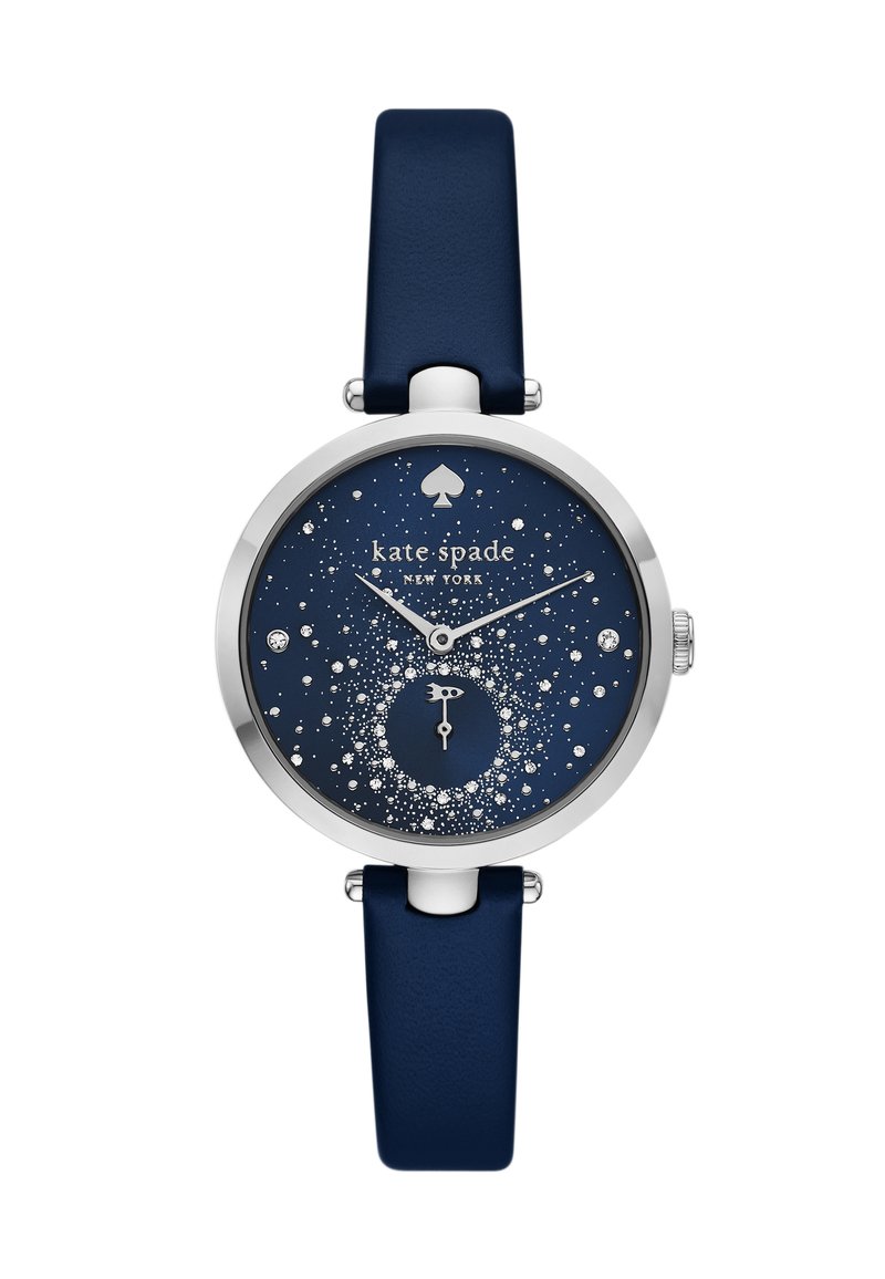 Mörkblå klocka med ett runt silverfärgat hölje och en glittrande stjärnhimmel-dial. Utrustad med en liten subdial, silverfärgade visare och ett mjukt läderarmband.