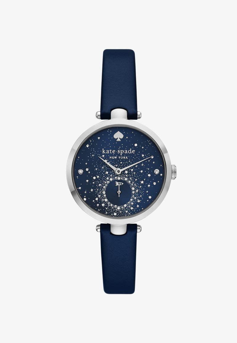 Mörkblå klocka med ett runt silverfärgat hölje och en glittrande stjärnhimmel-dial. Utrustad med en liten subdial, silverfärgade visare och ett mjukt läderarmband.