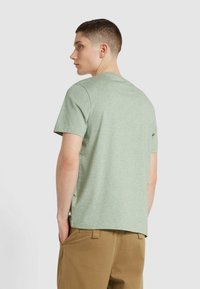 T-shirt verde menta a maniche corte con scollatura rotonda, realizzato in tessuto morbido. Il design presenta una vestibilità comoda e una texture liscia.