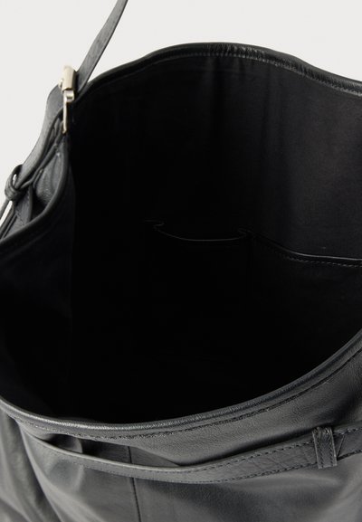 Geantă de mână din piele neagră cu partea de sus parțial deschisă, arătând un interior spațios din material textil și un buzunar mic interior.