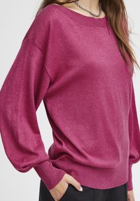 Fuchsia tröja med avslappnad passform, ribbade ärmslut och halsringning. Mjuk textur med subtil lyster, med långa ärmar och en avslappnad silhuett.