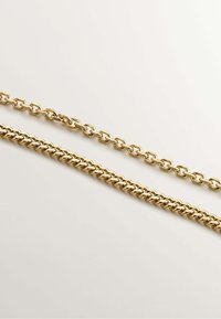 Collares de cadenas de metal dorado, uno con eslabones entrelazados y un acabado suave, y el otro con un diseño de eslabones retorcidos, ambos brillantes.
