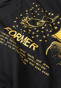 Camiseta de algodón negra con estampado gráfico amarillo de un pato, estrellas y la palabra "FORMER." Incluye texto con frases divertidas e informales.