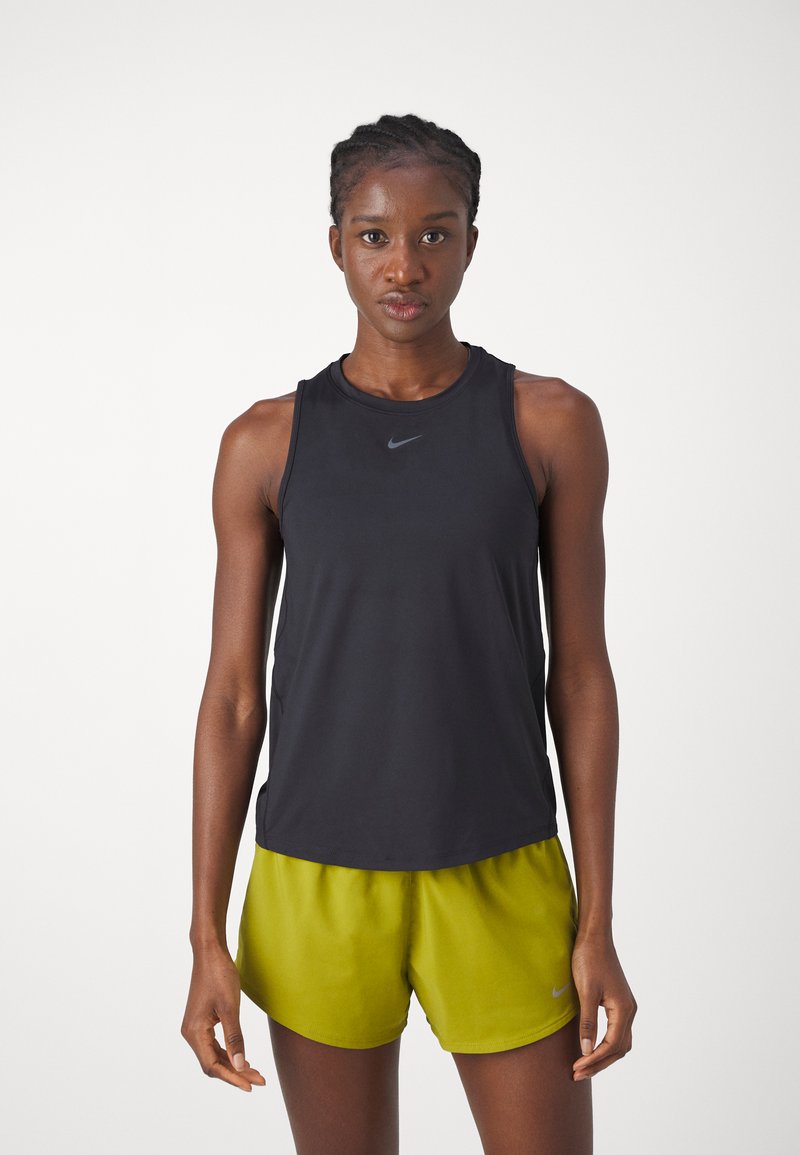 Schwarzes ärmelloses Sportoberteil mit rundem Ausschnitt, kombiniert mit leuchtend grünen Shorts. Beide Teile bestehen aus glattem, leichtem Material und tragen dezente Markenlogos.