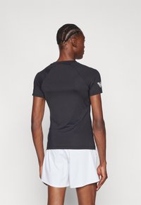 Zwart sportshirt met korte mouwen en een getailleerd ontwerp, gemaakt van een gladde stof. Heeft een ronde halslijn en een logo op de linker schouder.