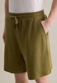 Olivgrüne Shorts aus strukturiertem Stoff, mit einem elastischen Bund und Kordelzug, seitlichen Taschen und einer lässigen Passform.