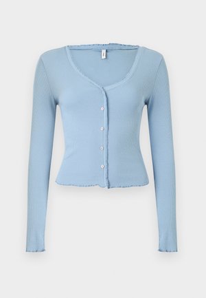 Φωτεινό μπλε, ριμπ πλεκτή ζακέτα με μακριά μανίκια, μικρά λευκά κουμπιά, V-λαιμόκοψη και ελαφρώς βολάν στις άκρες του γιακά, των μανσετών και του τελειώματος.