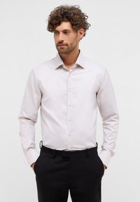 Camicia grigia chiara con colletto a punta, maniche lunghe e chiusura con bottoni. Presenta una sottile trama e bottoni in contrasto.