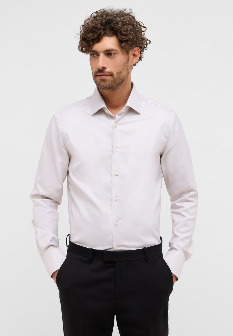 Camicia grigia chiara con colletto a punta, maniche lunghe e chiusura con bottoni. Presenta una sottile trama e bottoni in contrasto.