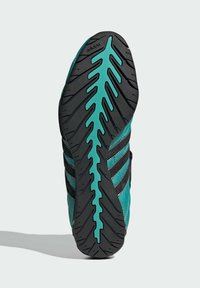 Sort og teal atletisk sko sål med en tekstureret gummioverflade, der har et zigzag-mønster og adidas-branding langs kanten.
