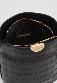 Borsa a mano in pelle nera con texture a rilievo in cocco. Chiusura e dettagli in oro. Interno foderato in nero e etichetta con logo.