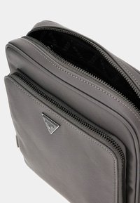 Grau strukturiertem Stoffbeutel mit zwei Reißverschlussfächern. Verfügt über ein metallic Logo-Tag und eine strukturierte Oberfläche. Die Reißverschlüsse haben passende Zuglaschen.