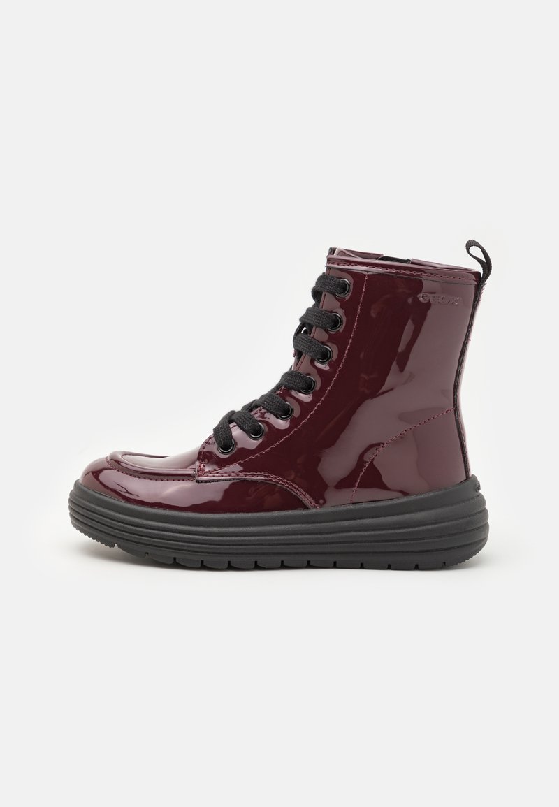 Burgundy patent leather ankle boots with black laces, a round toe, and a thick black rubber sole. Features a pull tab at the back.