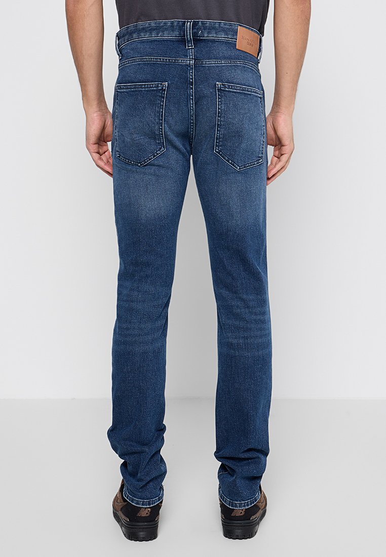 Blaue Denim-Jeans mit schlanker Passform, featuring eine mittelhohe Taille, zwei Gesäßtaschen und einem braunen Lederpatch am Bund.