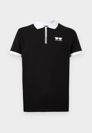 Melnā īsroku polo krekls ar baltiem apkakli un piedurkņu manšetēm, priekšpuses rāvējslēdzēju un mazu baltu logotipu ar saules brillēm un tekstu "Karl Lagerfeld".