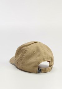 Beżowa bawełniana czapka baseballowa z wygiętym daszkiem, teksturowana tkanina, regulowany pasek z tyłu oraz mała czarna metka z logo.