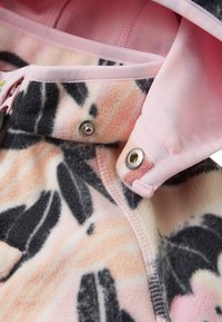 Fleece jacket featuring a pink floral pattern with black accents. Fastened with metallic snaps, inside lined with a smooth pink fabric.