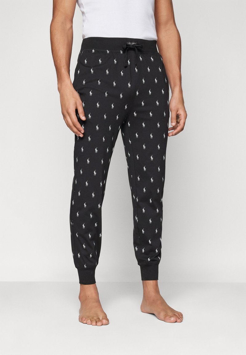 Pantalon de jogging noir avec un motif subtil de logo de cheval blanc, taille élastique avec cordon de serrage, et bas resserrés. Texture de tissu douce.
