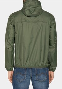 Lättviktsjacka i olivgrön färg med huva, elastiska manschetter och dragen nederkant. Tillverkad av ett slätt, vattenavvisande material.