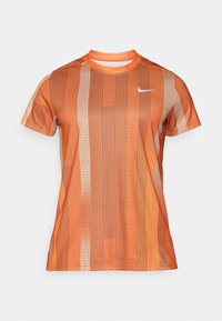 Narančasta majica s kratkim rukavima s vertikalnim prugama u različitim nijansama i geometrijskim uzorcima, s bijelim Nike logotipom na prsima.