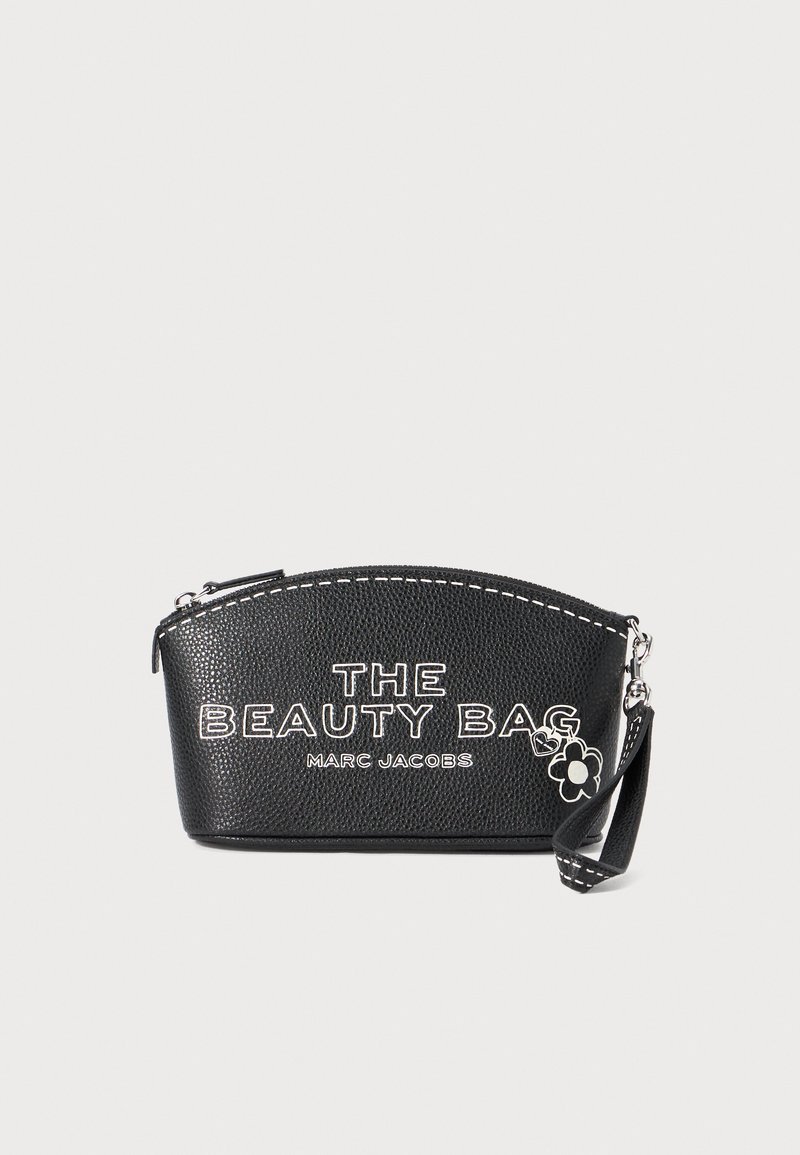 Czarna skórzana kosmetyczka o wytłaczanym wzorze, zaokrąglonym dnie, z białym napisem "THE BEAUTY BAG" oraz małym uroczym kwiatkiem przymocowanym na zawieszce.