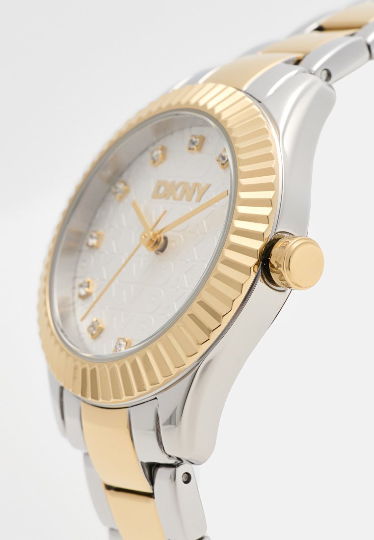 Orologio DKNY con finitura argento e dorato, quadrante bianco testurizzato, indicatori delle ore simili a diamanti, lunetta rigata e bracciale in acciaio inossidabile.