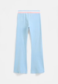 Gaiši zili izplestie bikses ar maigu tekstūru, kas rotātas ar kontrastējošu svītrojumu jostu rozā un zilā krāsā. Attēlots skats no aizmugures.