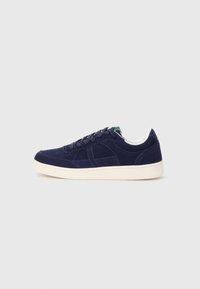Tenisi din suede bleumarin, cu talpă din cauciuc albă, vârf rotund și șireturi de culoare albastru închis. Au detalii de cusătură subtile și o textură netedă.