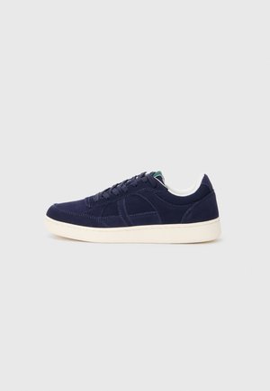 Baskets en suède bleu marine avec une semelle en caoutchouc blanc, bout rond et lacets bleu foncé. Présente des détails de couture subtils et une texture lisse.