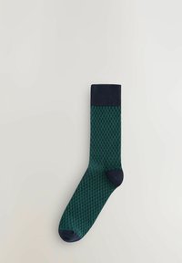 Chaussette verte et marine à motifs avec un design texturé, un bord-côte, et un talon renforcé ; fabriqu�ée en matériau extensible et respirant.
