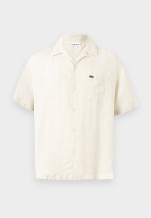 Rövid ujjú, bézs színű lenvászon ing gallérral, elöl gombokkal, mellzsebbel és a zsebén kis zöld krokodil logóval.