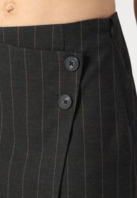 Gonna nera a righe con una trama a ossatura di pesce, caratterizzata da due bottoni neri in vita e un design elegante e su misura.