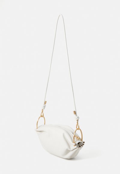 Balta ādas rokassoma ar noapaļotu formu, ar rāvējslēdzēju, regulējamu siksnu un zelta krāsas aksesuāriem.