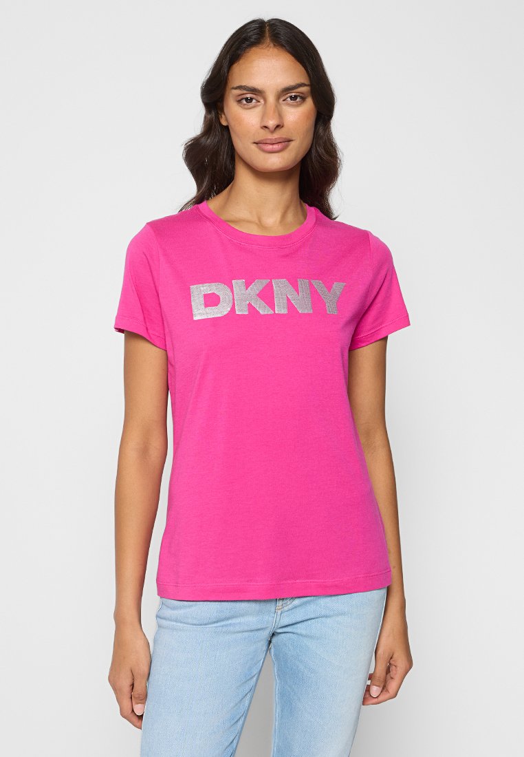 Jasnoróżowa koszulka wykonana z bawełny, z krótkimi rękawami, z dużym srebrnym logo "DKNY" na wysokości klatki piersiowej. Klasyczny okrągły dekolt.