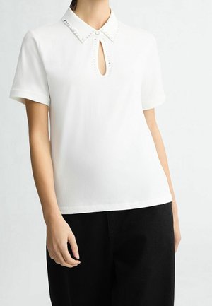 Weiße Bluse mit kurzen Ärmeln und Kragen, der eine Schlüsselloch-Öffnung sowie dekorative Nieten entlang des Halsausschnitts aufweist. Glatter Stoff, lockere Passform.