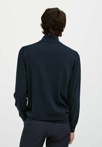 Marinefarbener Langarm-Pullover mit geripptem Kragen und Bündchen, aus weicher Stoffqualität; zeichnet sich durch eine glatte Textur und eine taillierte Passform aus.