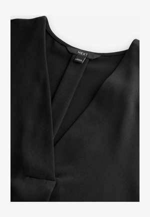 Črna bluzica iz mehkega, teksturiranega materiala. Ima V-izrez in prekrivne sprednje panele. Oznaka blagovne znamke je vidna na hrbtni strani.