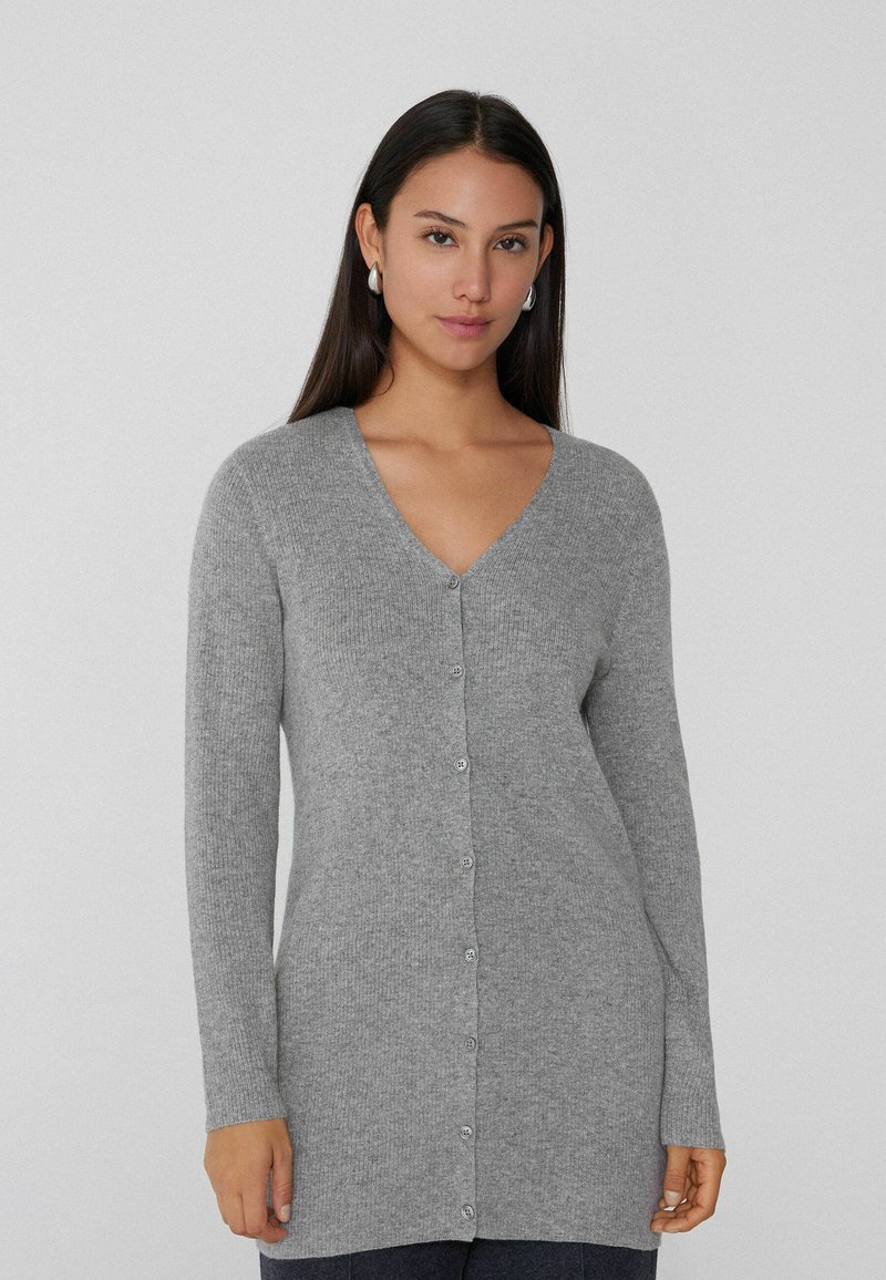 Grau melierter Cardigan aus weichem Strickmaterial, mit V-Ausschnitt, langen Ärmeln und Knöpfen vorne. Klassisches, gerade geschnittenes Design mit geripptem Muster.