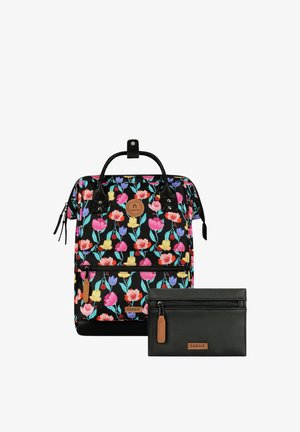 Schwarzer Rucksack mit buntem Blumenmuster und Lederakzenten neben einem kleinen schwarzen Reißverschlusstäschchen mit Lederdetails, beide mit CABAIA-Logo.