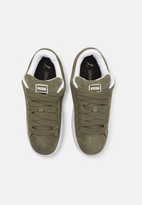 Baskets en suède vert olive avec semelles blanches, dotées d'un col rembourré, de lacets épais et d'un onglet de marque sur la languette.