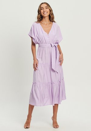 Lilac maxi dress with a V-neck, short sleeves, a tie belt, and tiered skirt. Made from lightweight fabric with button details along the neckline.